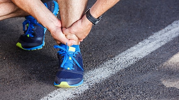 Male runner holding his hurt ankle