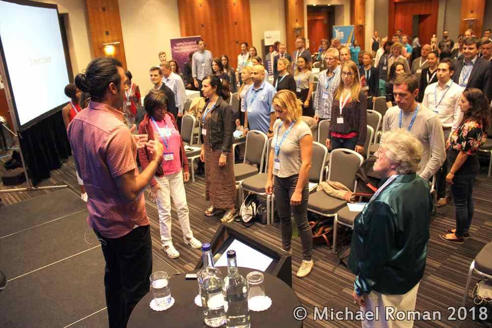 Posture Specialist addressing a standing audience during a workshop