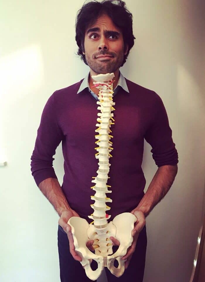 Postural Specialist holding a model spine in front of his body